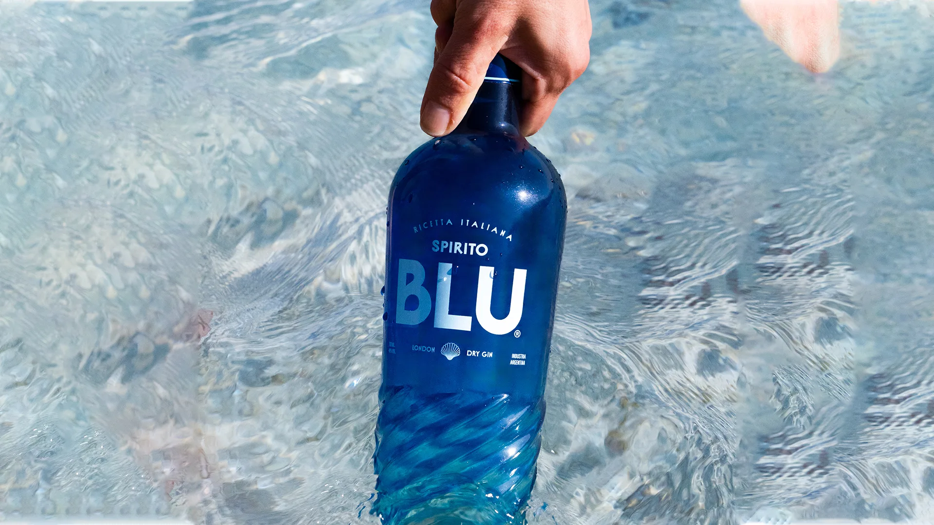 Una mano sumerge la botella de Spirito Blu en el agua
