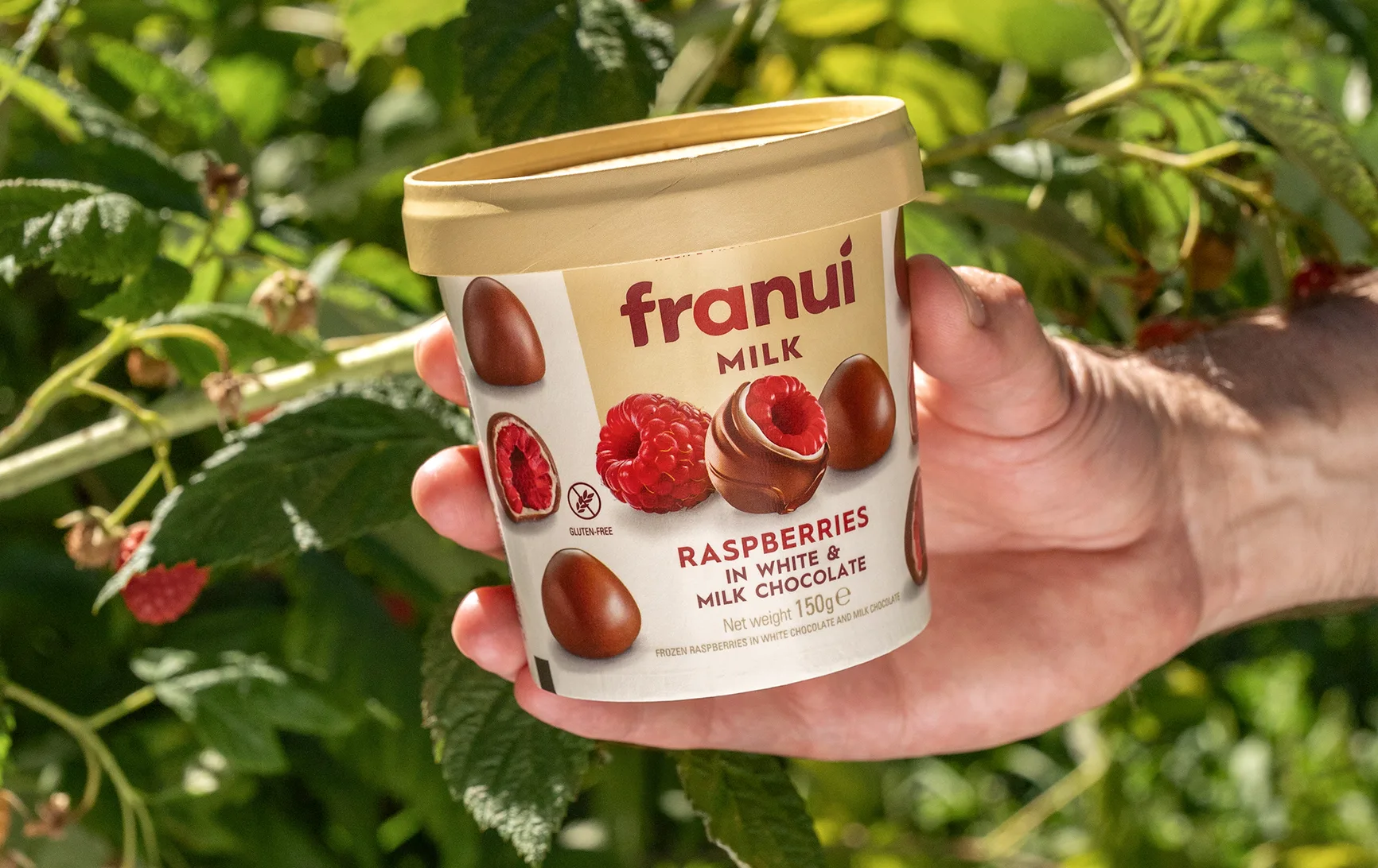 Pote de Franuí Milk entre frambuesas